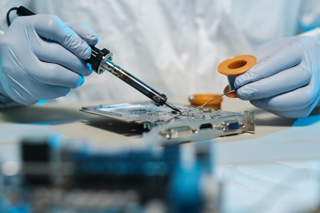 Gloved hands of repairman with soldering iron and tin