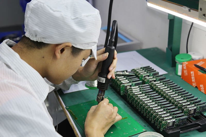 An employee in a factory engaged in the assembly of electronic devices, showcasing attention to detail and craftsmanship.