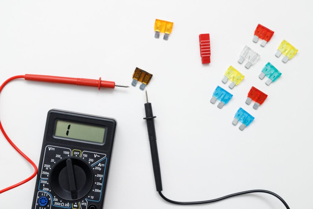 Digital multimeter for measuring electrical elements and car fuses on a white background