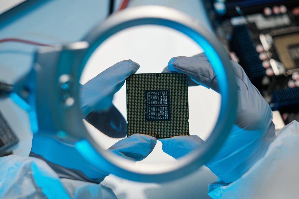 Magnifying glass and gloved hands of scientist holding microchip