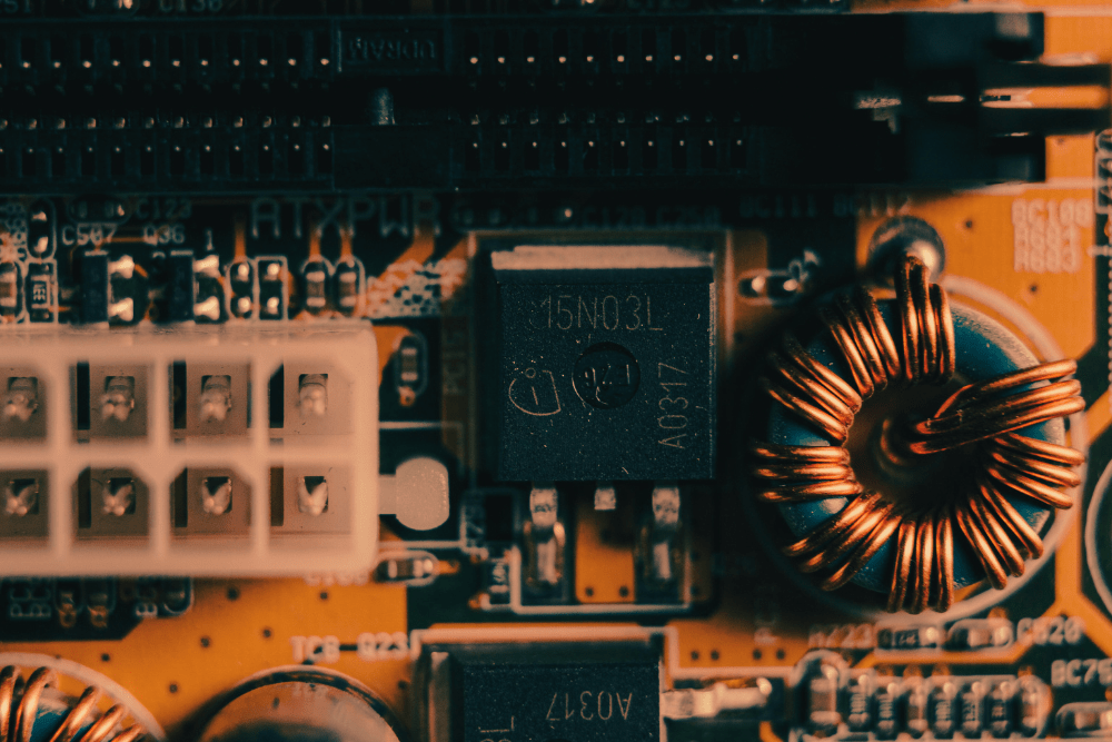 Close-up image of a computer motherboard showcasing electronic components such as a power connector, a MOSFET transistor labeled "15N03L," and copper-wound inductors.