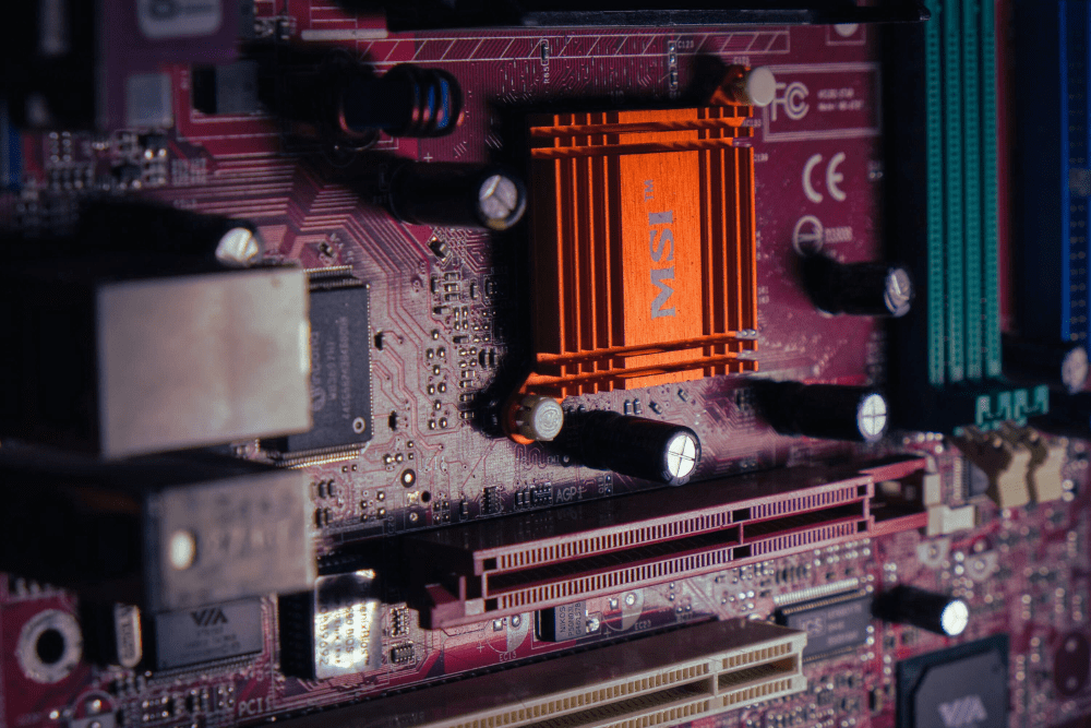 A close-up of an MSI motherboard showcasing electronic components, circuits, and an orange heatsink.