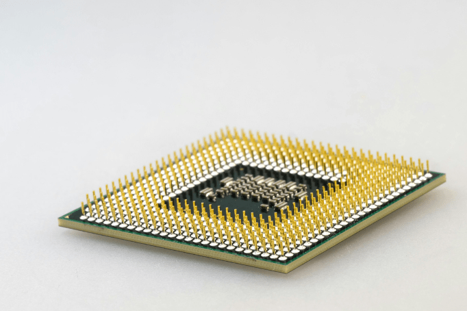 A close-up photograph of a computer processor (CPU) with gold-plated pins, placed on a white background.